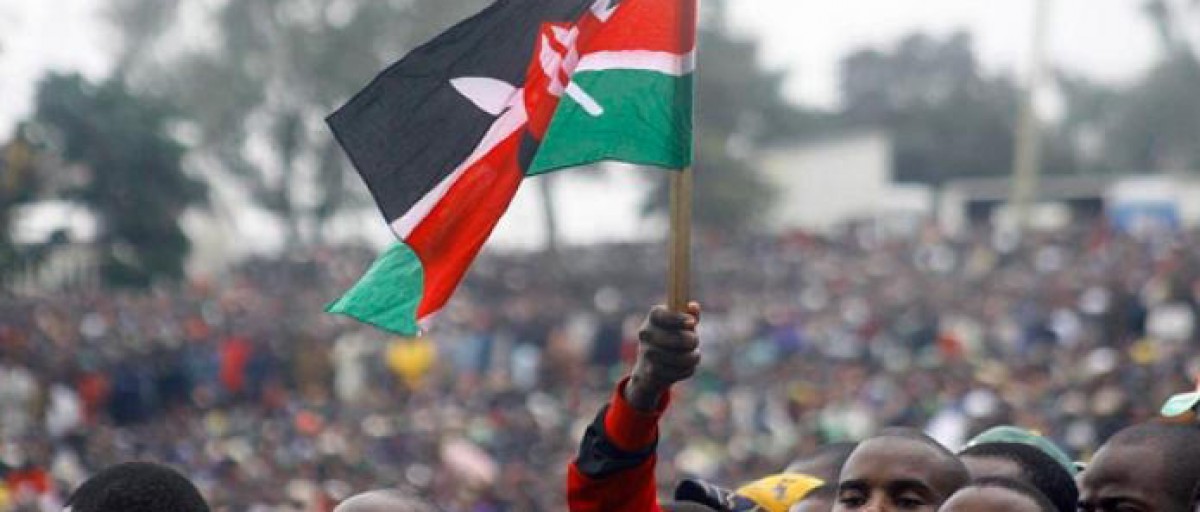 A flag of kenya being flag by a kenyan during a rally